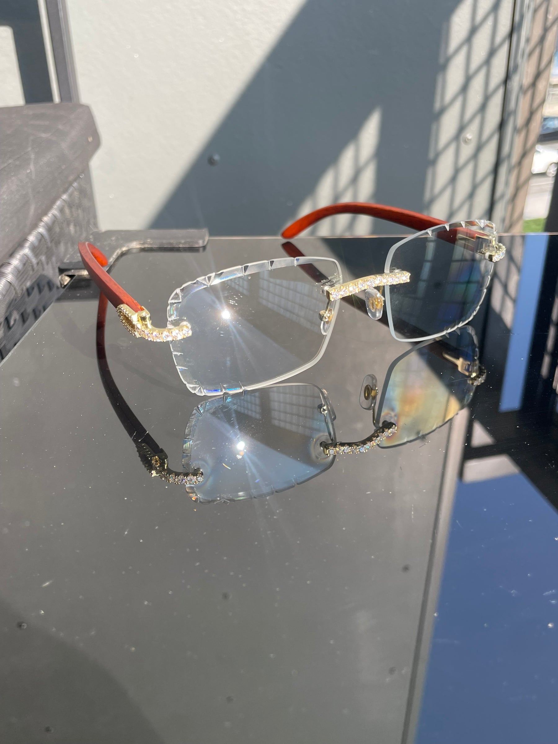 Rimless moissanite glasses displayed on a reflective surface in sunlight